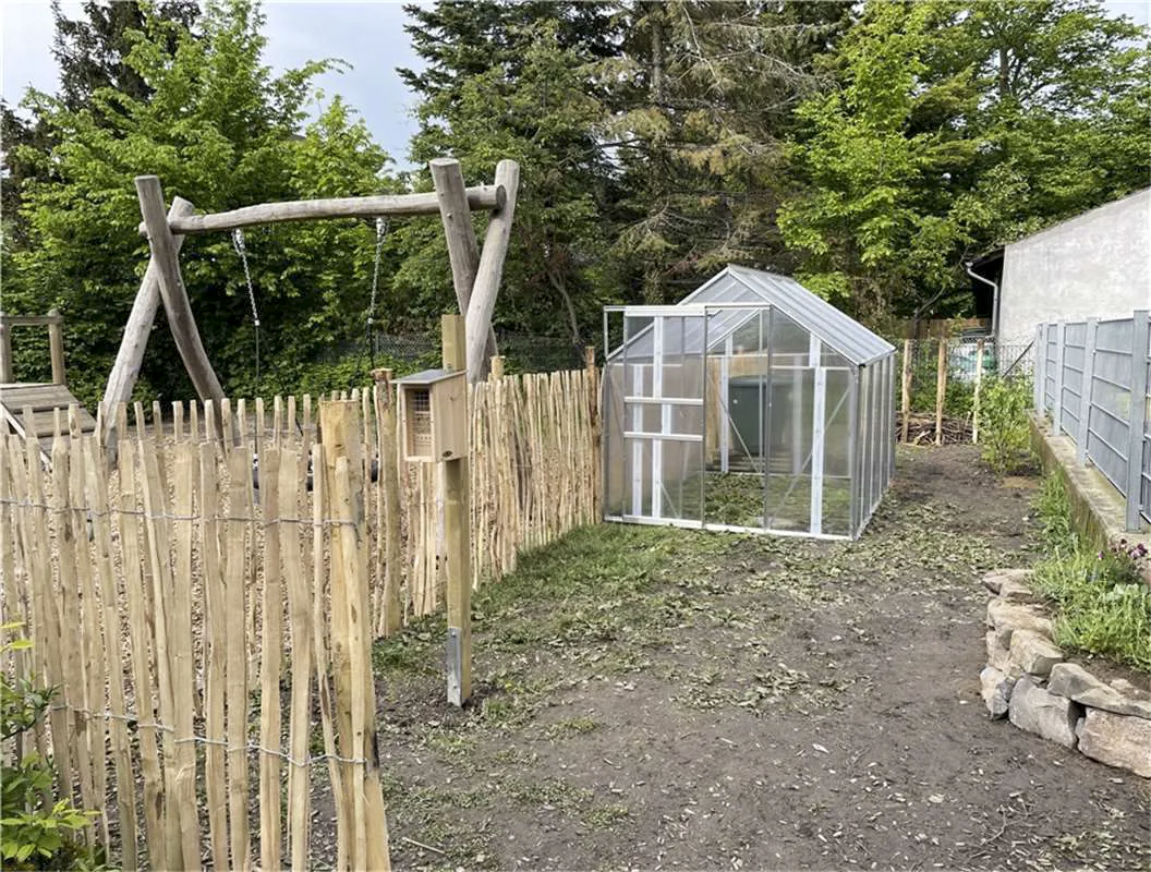 Schulgarten Meckenheim: fertiger Garten mit Vitavia Gewächshaus Planet, Modell 5000  in Alu und Hohlkammerplatten umgeben von Holzzaun